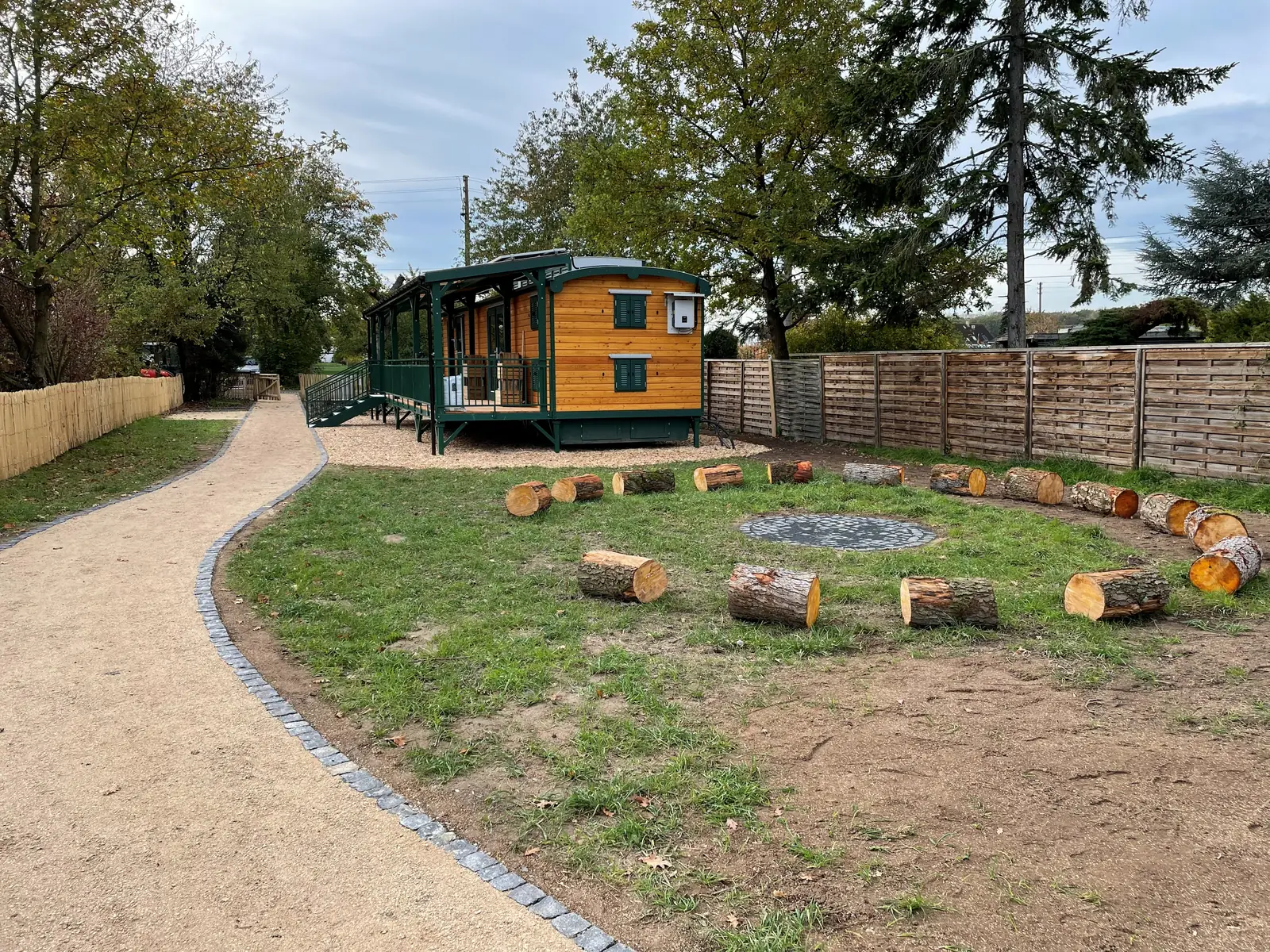 Naturnahe Spielfläche mit Sitzkreis und Bauwagen