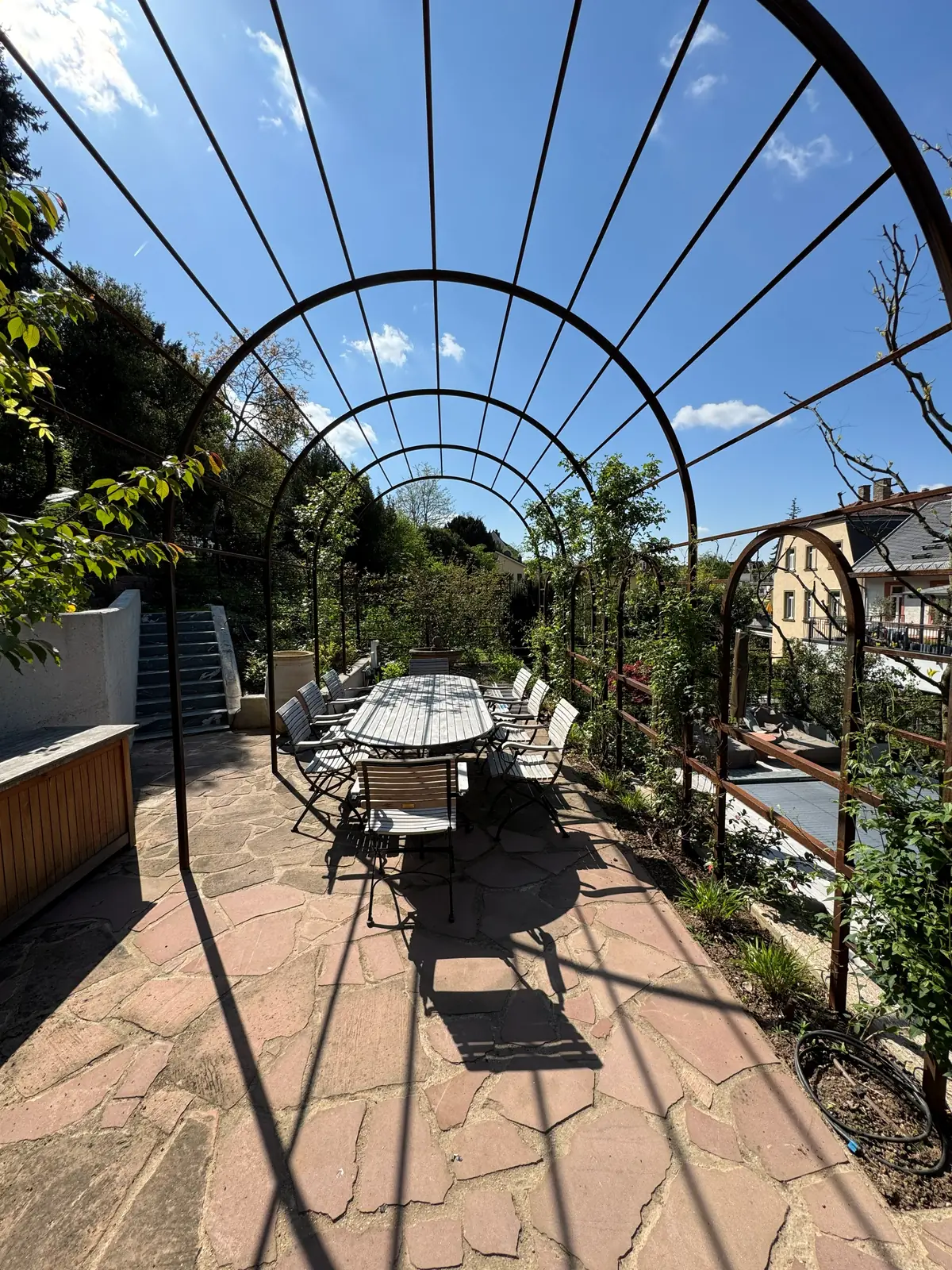 Natursteinweg und Sitzplatz unter einer Pergola