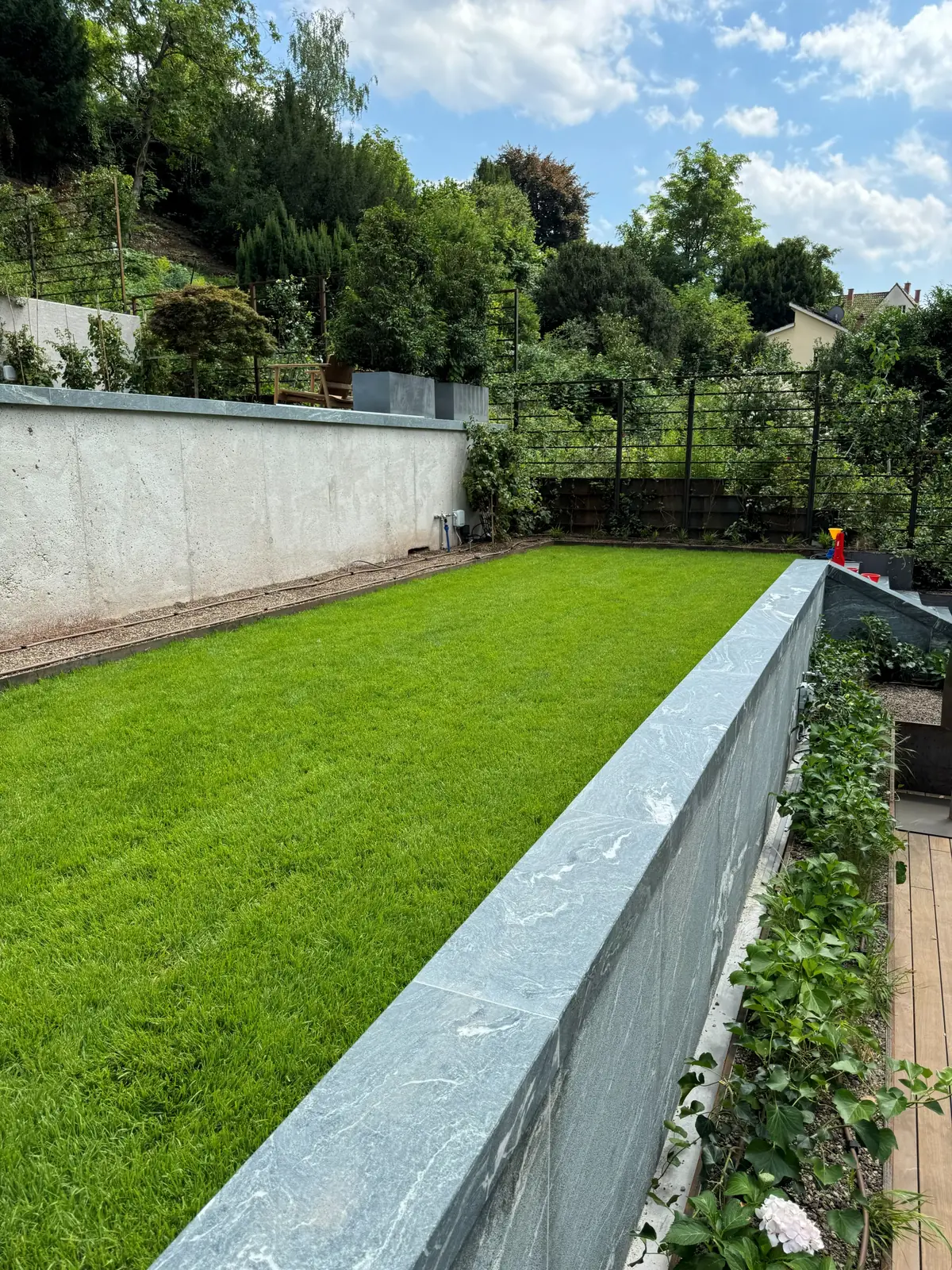 Grüne Gartenebene oberhalb einer Stützwand